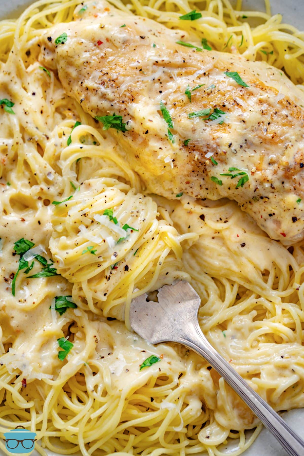 Looking down on a large serving of Crock Pot Angel Chicken with a fork in the pasta. 