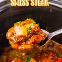 A serving spoon with a scoop of Swiss Steak above a Slow Cooker.