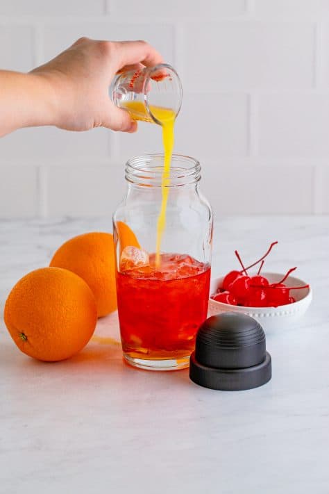 Alcohols being added to cocktail shaker.